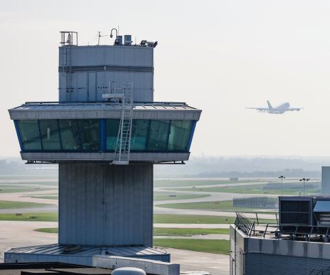 An aircraft takes off behind an airport air traffic control tower
