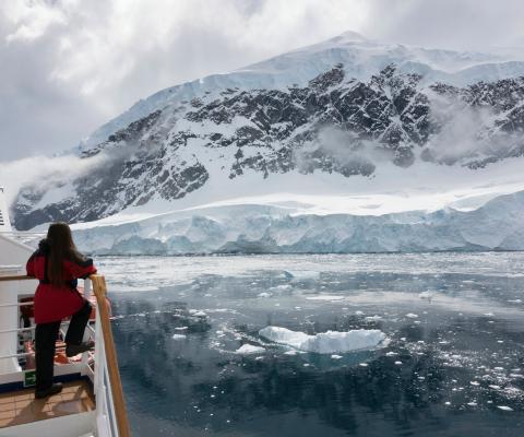 Woman looks at ice shelf during Antartica cruise
