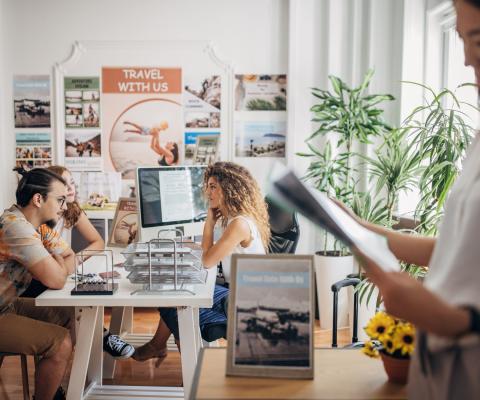Clients chat to a travel agent in a busy travel agency