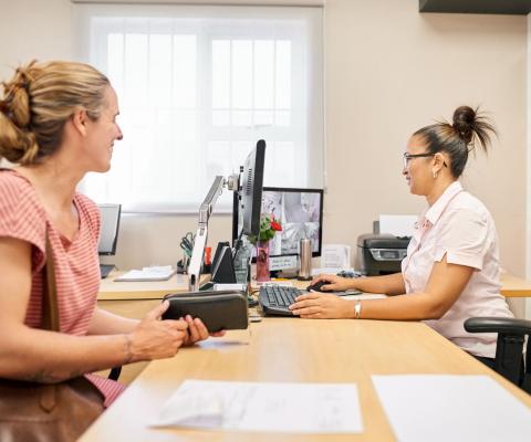 Travel agent working at her desk with a female customer at tiles store office stock photo