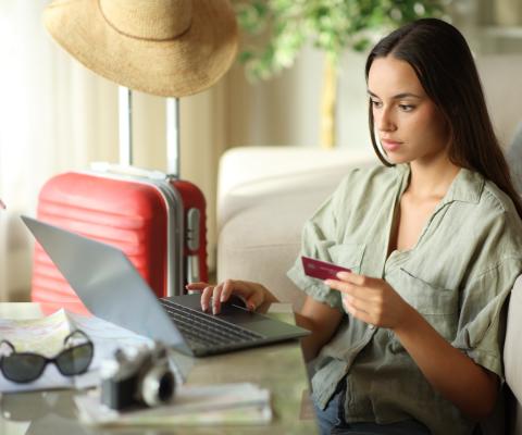 A woman looks at her card while using a laptop