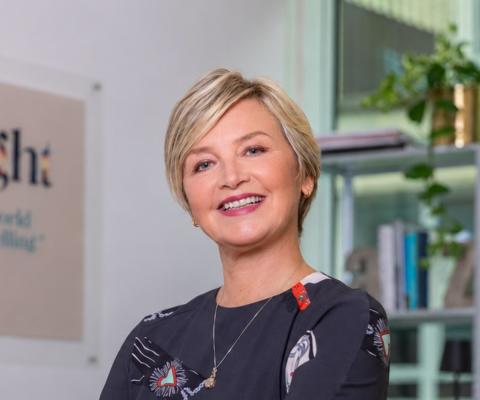Professional head shot of white woman with short blonde hair. She is smiling. 