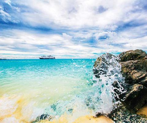 Caribbean cruise waves crashing a rock on the beach iStock_77635807
