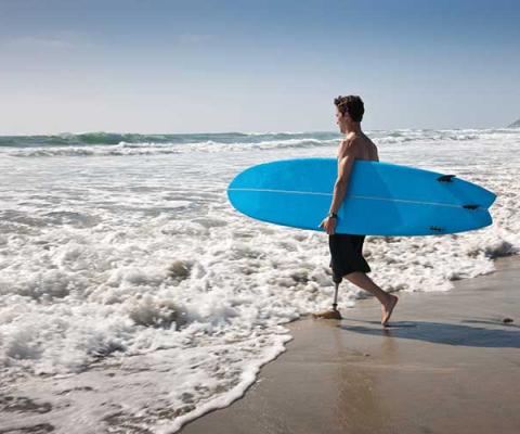 Man with surfboard entering sea