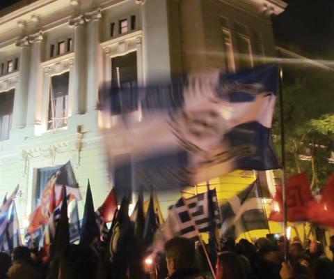 Crowd waves Greek flags in a street procession