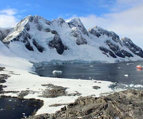 Ship in polar seas against mountainous landscape