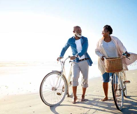 Over-50s couple with bicycles on the beach