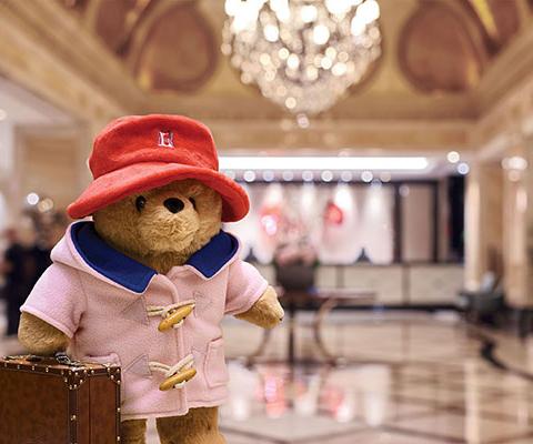 Paddington has swapped his traditional blue duffle coat for a new Langham-pink version