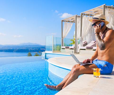 Holidaymaker using laptop by pool