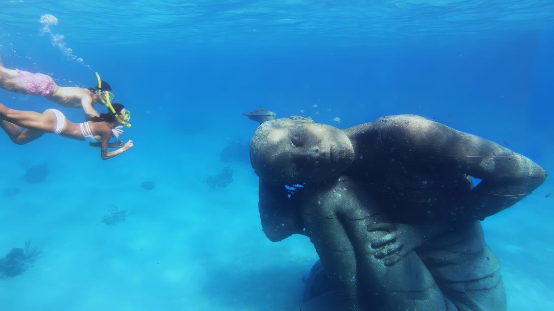 Two women diving to see underwater sculptures in Bahamas Heritage Park