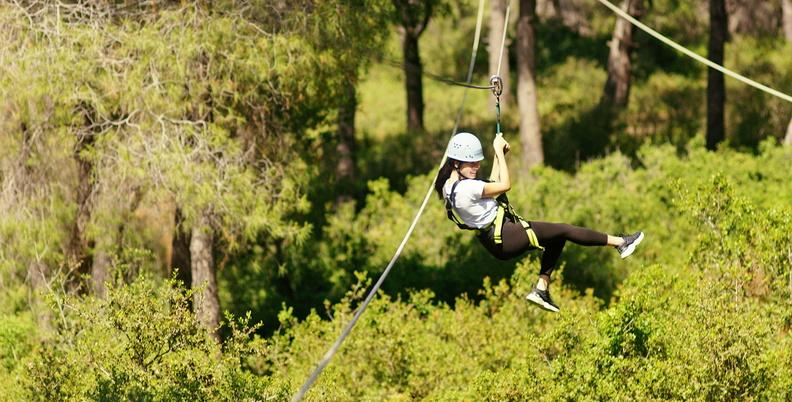 Young girl on a zip wire above tree canopy