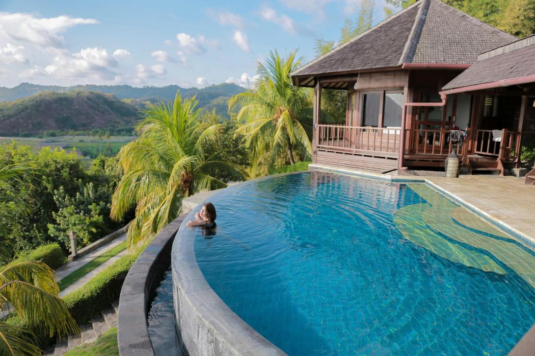 Villa with pool, woman in pool, looking over lush green landscape
