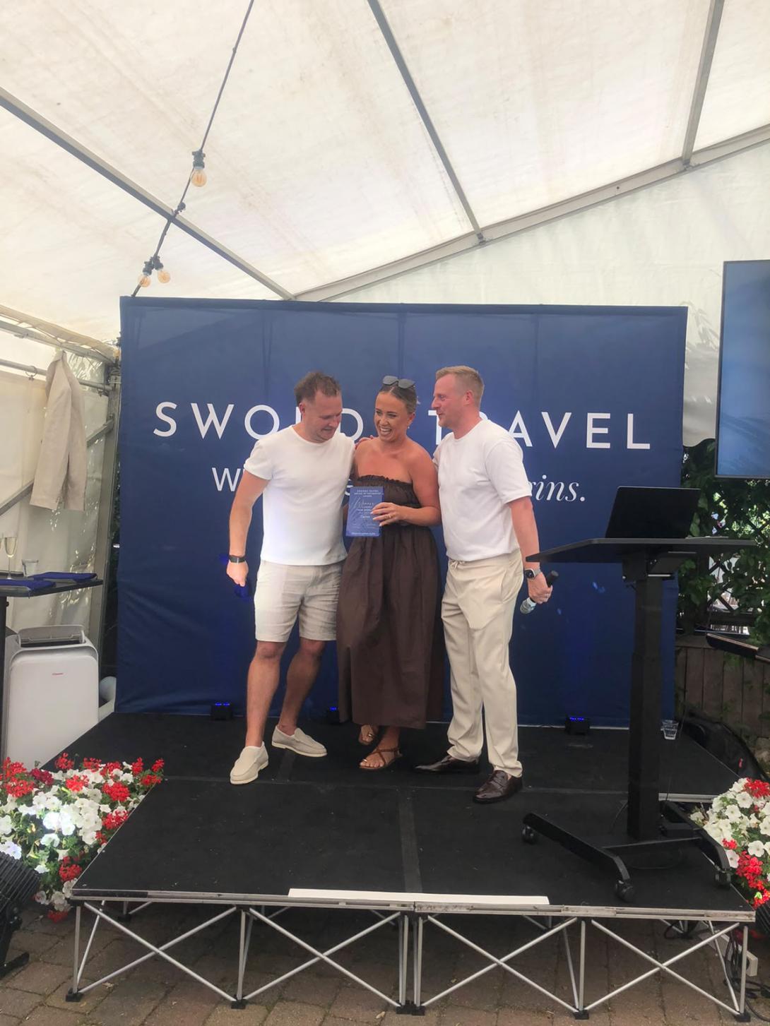 Woman getting award on stage, presented by two men