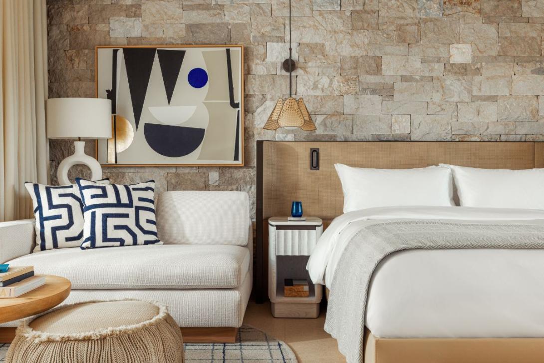 Luxury hotel room with neutral furnishings including bed and sofa