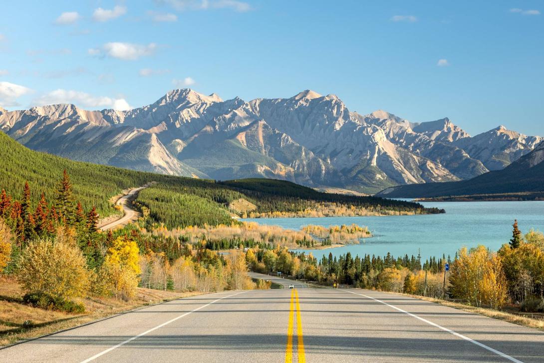 Mountain road leading to turquoise lake and autumn forest in Alberta Mountain road leading to turquoise lake and autumn forest in Alberta