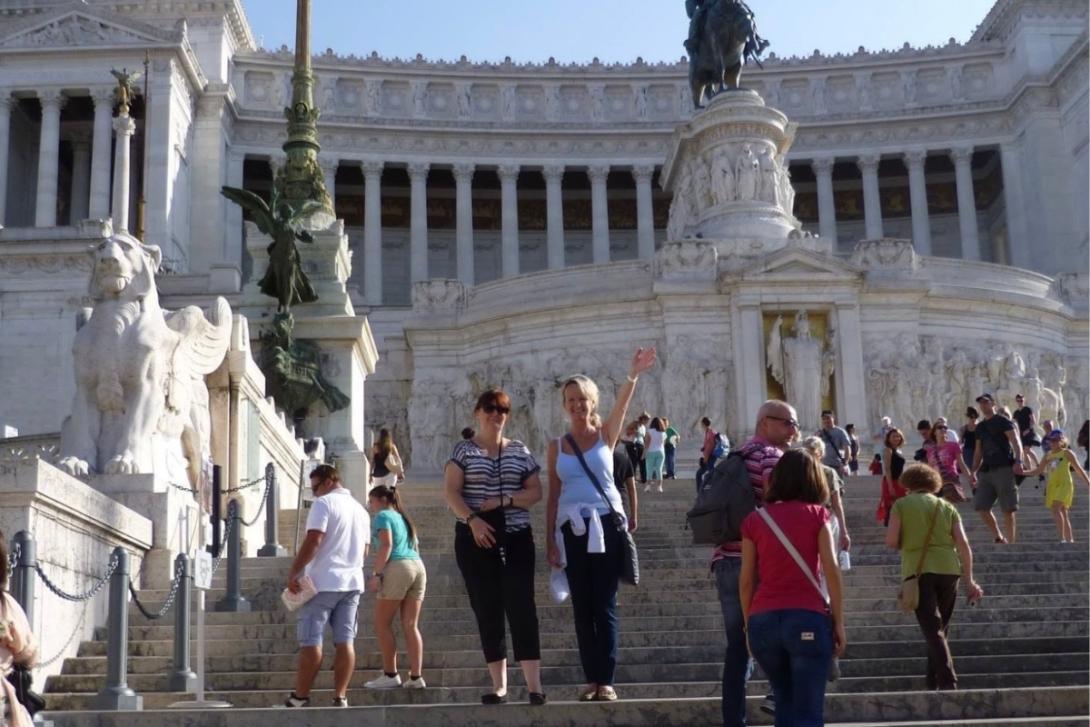 Two women standing on steps and smiling in Italian city