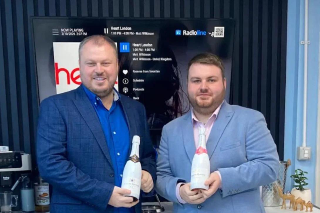 Two men smiling, each holding champagne