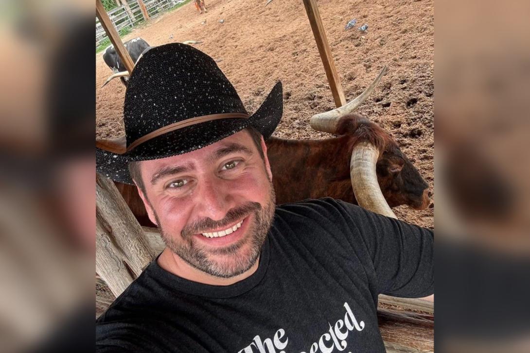 White man smiling wearing cowboy hat